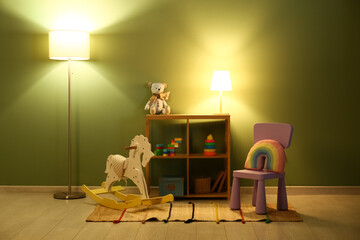 Interior of night children's room with glowing lamps, rocking horse, chair and many toys in...
