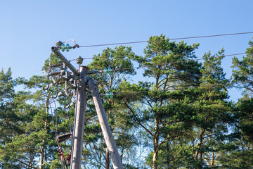 Electrical utility pole with power lines and insulators set against a blue sky and surrounded by...