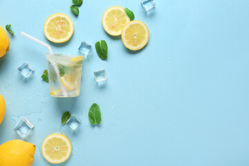 Frozen lemonade in shape of cup with straw, sliced lemons and mint on blue background