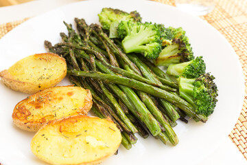 lean dish of cooked fried inflorescences of broccoli, asparagus growth and baked potatoes and Provencal herbs