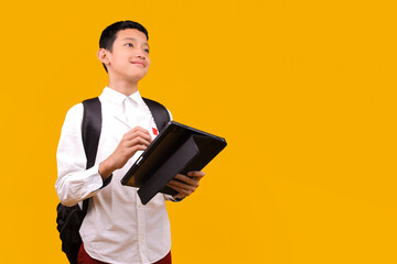 Happy Asian Student Boy Using Digital Tablet While Looking Up Isolated On Yellow Background