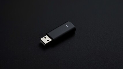 Fototapeta premium A sleek black USB flash drive resting on a textured dark surface, symbolizing modern technology and data storage solutions.