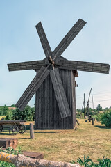 Historic 19th century wooden windmill in Pustoviitivka village, Sumy region, Ukraine. Traditional rural architecture with four wooden blades against clear blue sky