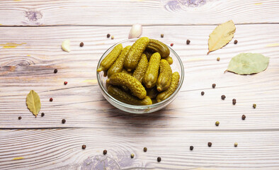 Pickled gherkins or cucumber in a bowl on a wooden background. No people.
