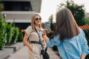 Woman taking photo of fashion model posing outdoors
