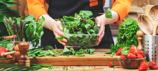 passionate chef carefully arranges fresh vegetables in a bowl, surrounded by various greens and...
