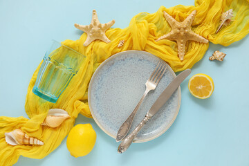 Table setting with plate, cutlery, glass, starfishes and seashells on blue background, closeup