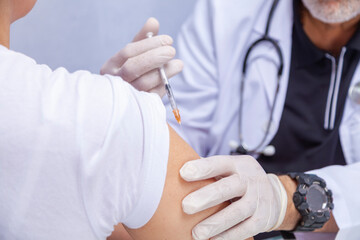 Hands of a doctor administering a vaccine to a female patient in a doctor's office.