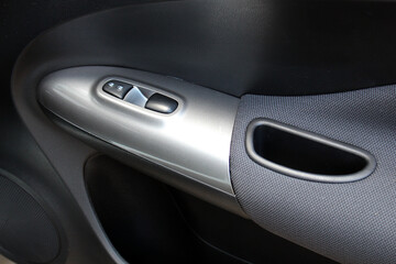 Door handle of modern car. New car windows control panel. Grey interior of the luxury modern car. Passenger door trim. Car interior details.