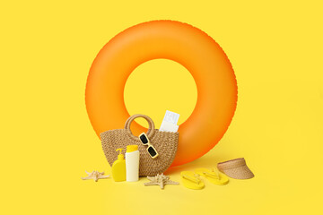 Inflatable ring, bottles of sunscreen cream and beach accessories on yellow background