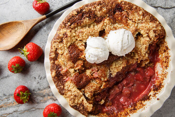 Strawberry cobbler pie with ice cream close-up in baking dish on table. Horizontal top view from above