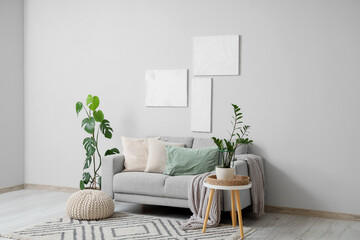 Interior of stylish modern living room with grey sofa, houseplants and pictures