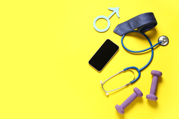 Male sign with smartphone, tie, stethoscope and dumbbells on yellow background. Prostate cancer...