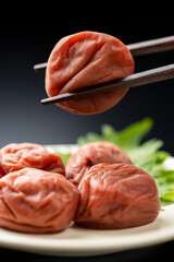 黒背景に箸で持ち上げた梅干し