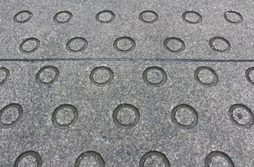 Closeup texture of asphalt road with circular indentation. Concrete slope with antislip ring hole background.	