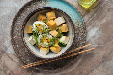 Bowl of smoked tofu with marinated egg on a brown granite background, horizontal shot, top view