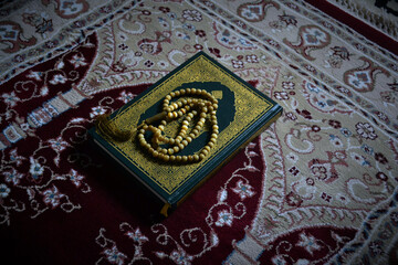 Holy quran and prayer beads on dark background