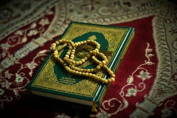Holy quran and prayer beads on dark background