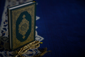 Holy quran and prayer beads on dark background