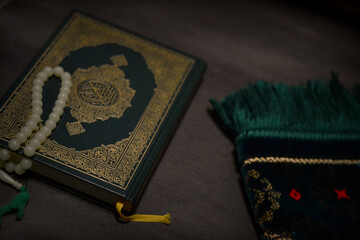 Holy quran and prayer beads on dark background