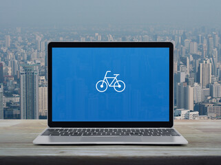 Bicycle flat icon on modern laptop computer screen on wooden table over city tower and skyscraper, Business bicycle shop online concept