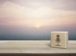 Microphone flat icon on wood block cube on wooden table over city tower and skyscraper at sunset, vintage style, Business communication concept