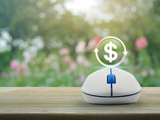 Money transfer icon on wireless computer mouse on wooden table over blur pink flower and tree in garden, Business currency exchange online service concept