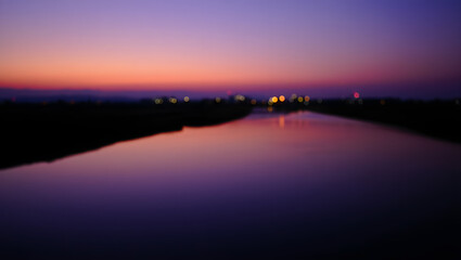 Fototapeta premium Blurred river reflects the colorful sunset sky at twilight
