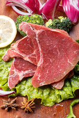Beef ribs with onion and lettuce on a wooden cutting board