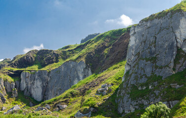 Rock face on the famous Antrim Coast with clear blue sky has a danger of landsides onto a public road