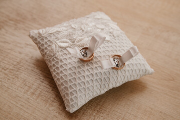 decorative pillow for holding gold wedding rings during a wedding ceremony with gold wedding rings on it