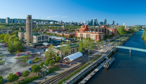 Aerial view of the Atwater Market and Lachine Canal in Montreal, Canada. People are enjoying the waterfront and market on a sunny day. - Powered by Adobe