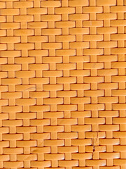 Close-up of an orange woven plastic texture in a crisscross pattern, ideal as a seamless background for design, craft, or packaging purposes.