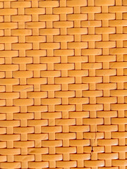 Close-up of an orange woven plastic texture in a crisscross pattern, ideal as a seamless background for design, craft, or packaging purposes.
