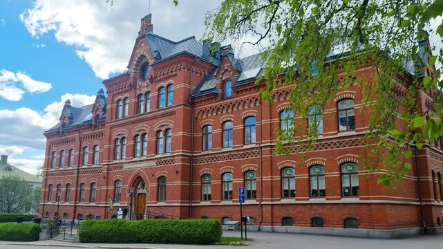Shot of Kyrkans Hus in Sundsvall, Sweden, under a partly cloudy sky. This historic red-brick building, blending Gothic and Romanesque styles, once served as a parish center