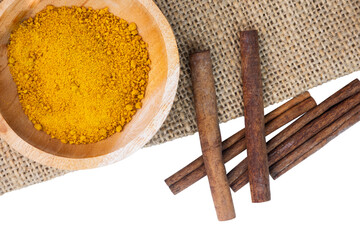 spices in a wooden bowl and cinnamon stick on burlap