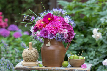 florales Arrangement mit Blumenstrauß mit pink Dahlien, Hortensienblüten, Schmuckkörbchen, Phacelia und Feder-Nelken im rustikalen Krug