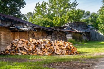 Pile of Firewood Logs Stacked Outside Rustic Wooden Shed in Rural Countryside. Freshly Cut Firewood...