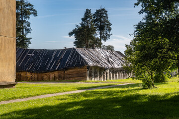 Old Wooden Building with Roof Covered by Protective Plastic in Green Countryside. Rustic Rural...