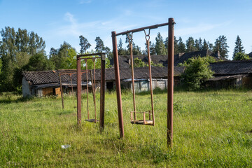 Rusty Swings in Abandoned Playground Overgrown with Grass. Forgotten Childhood — Rusty Playground in Overgrown Rural Field

.