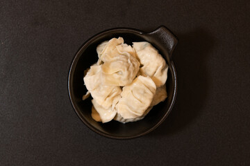 Chinese dumplings in a frying pan on a black background.