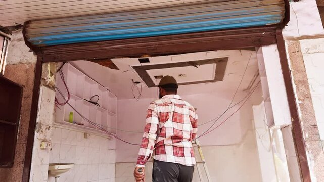 Man Renovates shop Interior While Standing on Ladder