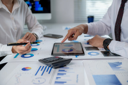 Two people are looking at a tablet with graphs on it