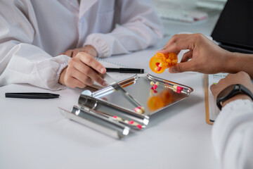 A person is holding a pill bottle and a pen on a table