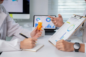 A doctor is holding a bottle of pills and talking to another doctor