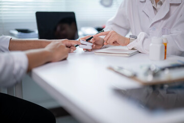 A doctor and patient are sitting at a desk with a clipboard