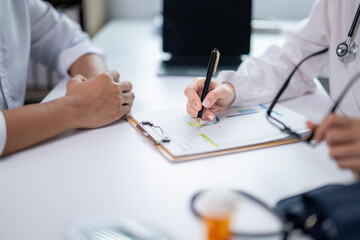 A doctor and a patient are sitting at a desk with a clipboard