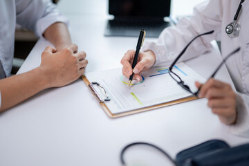 A doctor and patient are sitting at a desk with a clipboard in front of them