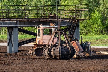 Old peat bog crawler excavator with large mechanical grabber bucket working under metal bridge...