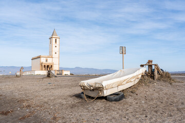 The Ermita de la Virgen del Mar with a covered boat in a minimalist setting under a sunny sky....